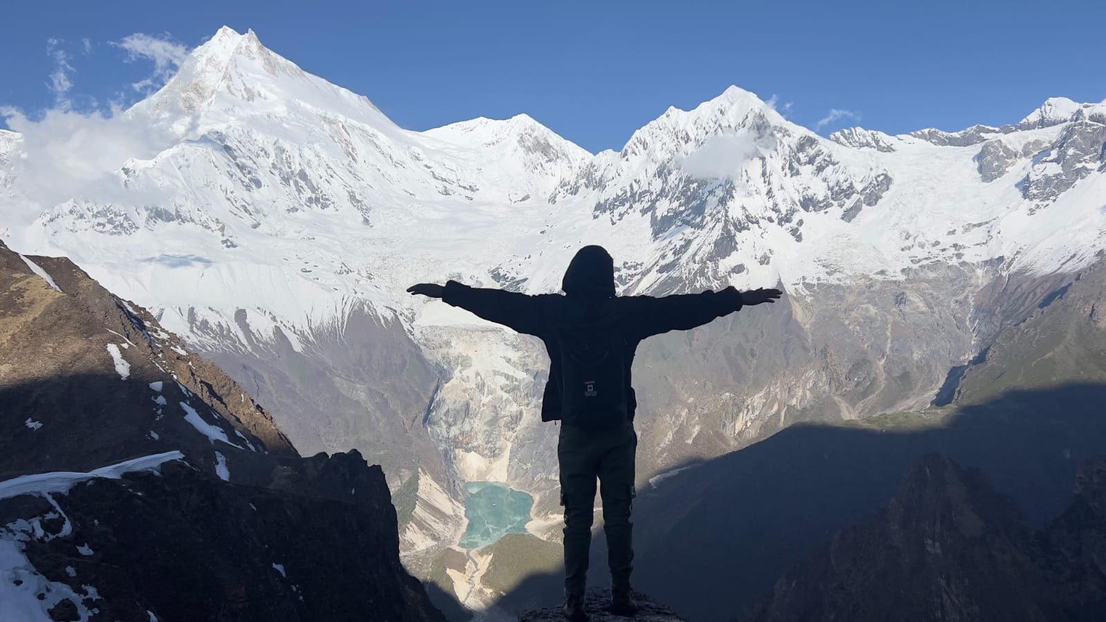 Trekkers relaxing on a stone viewpoint above Birendra Tal lake with stunning mountain views on the Manaslu Circuit trekking route in the Himalayas.