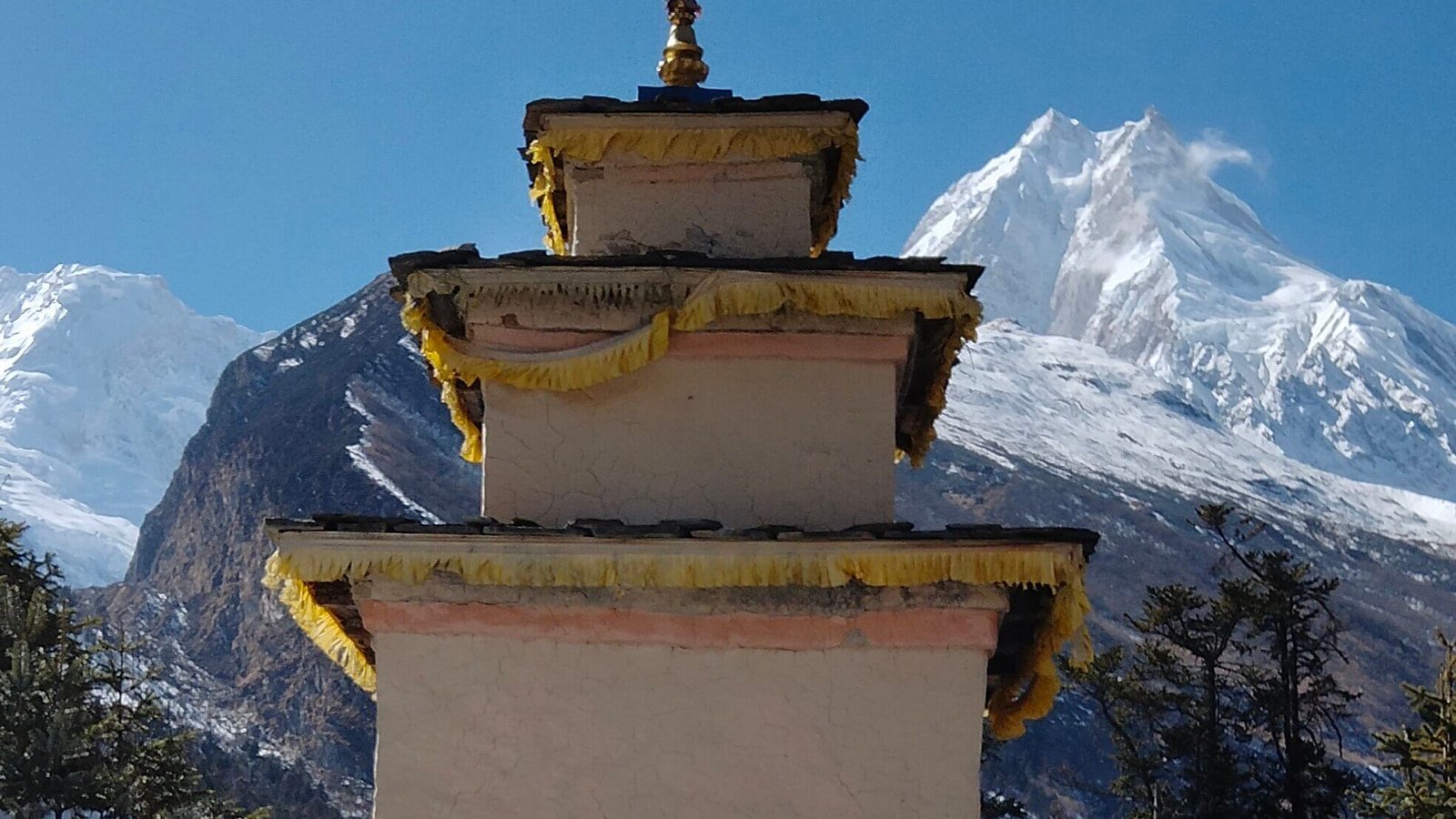 Chorten in Salya village with Mount Manaslu towering in the background under clear Himalayan skies