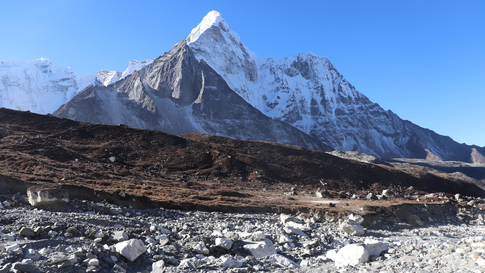 Trekkers navigating rugged Himalayan terrain on the Everest High Pass Trek with snow-covered peaks in the background
