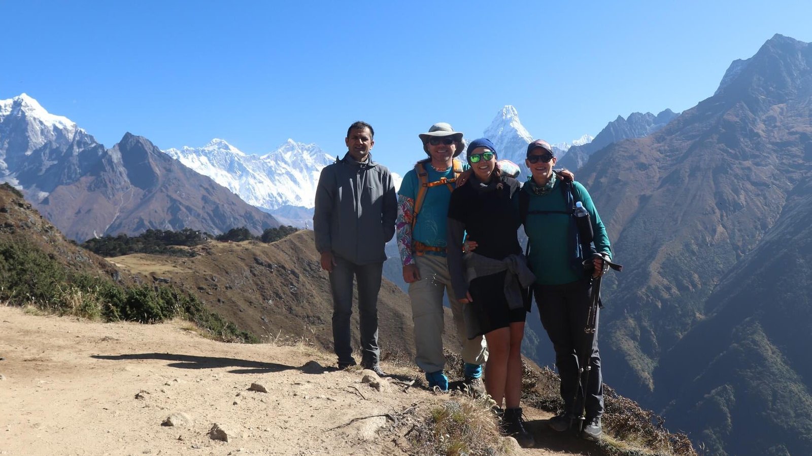 Group of trekkers posing with stunning backdrop of Mount Everest and Ama Dablam during Everest View Trek on a clear Himalayan morning.